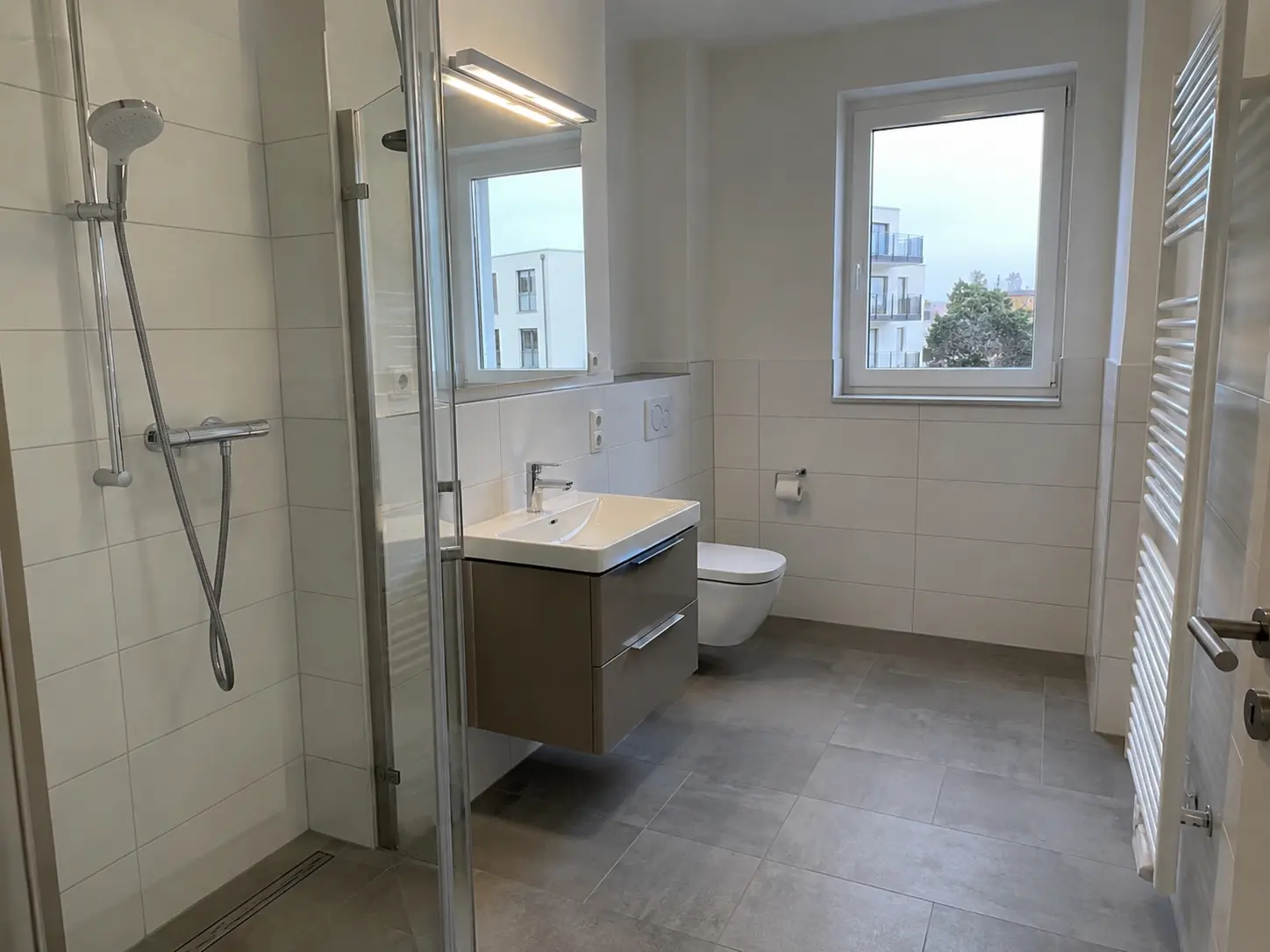Neu gefliestes Bad mit Glasdusche, Waschtisch und Fenster