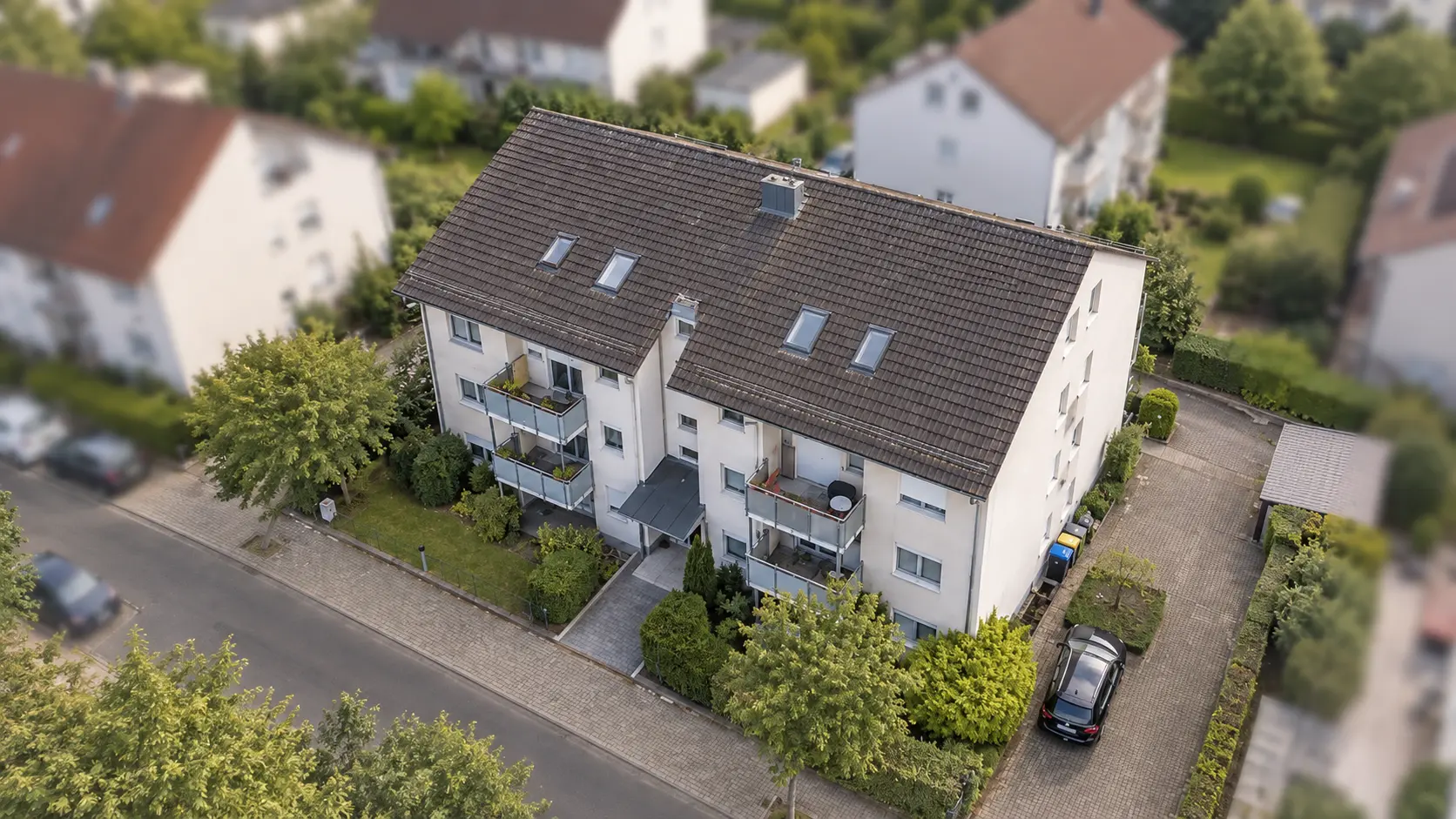 Mehrfamilienhaus mit Garten an einer Wohnstraße von oben