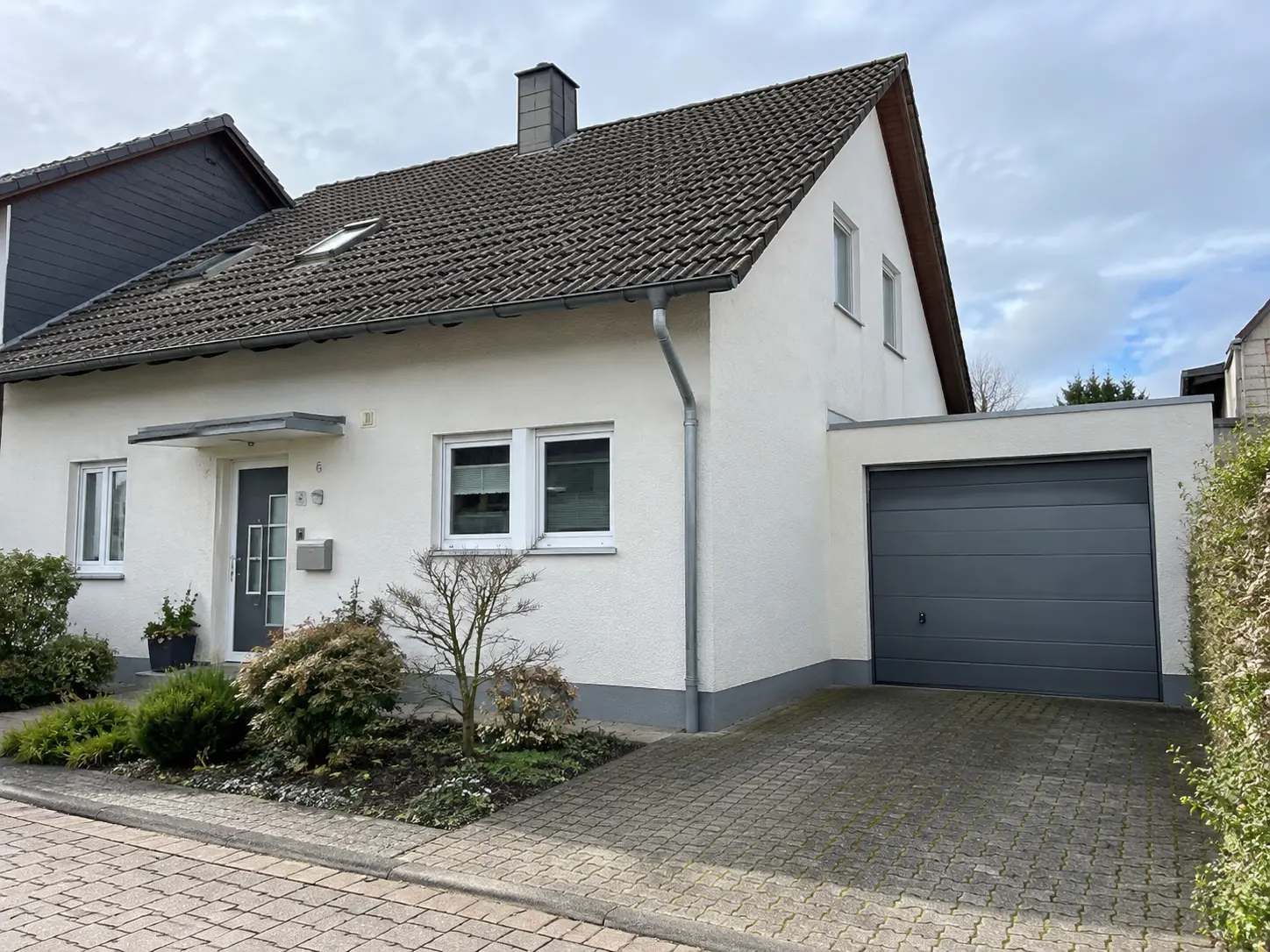Einfamilienhaus mit Satteldach und Garage, von der Straße aus gesehen