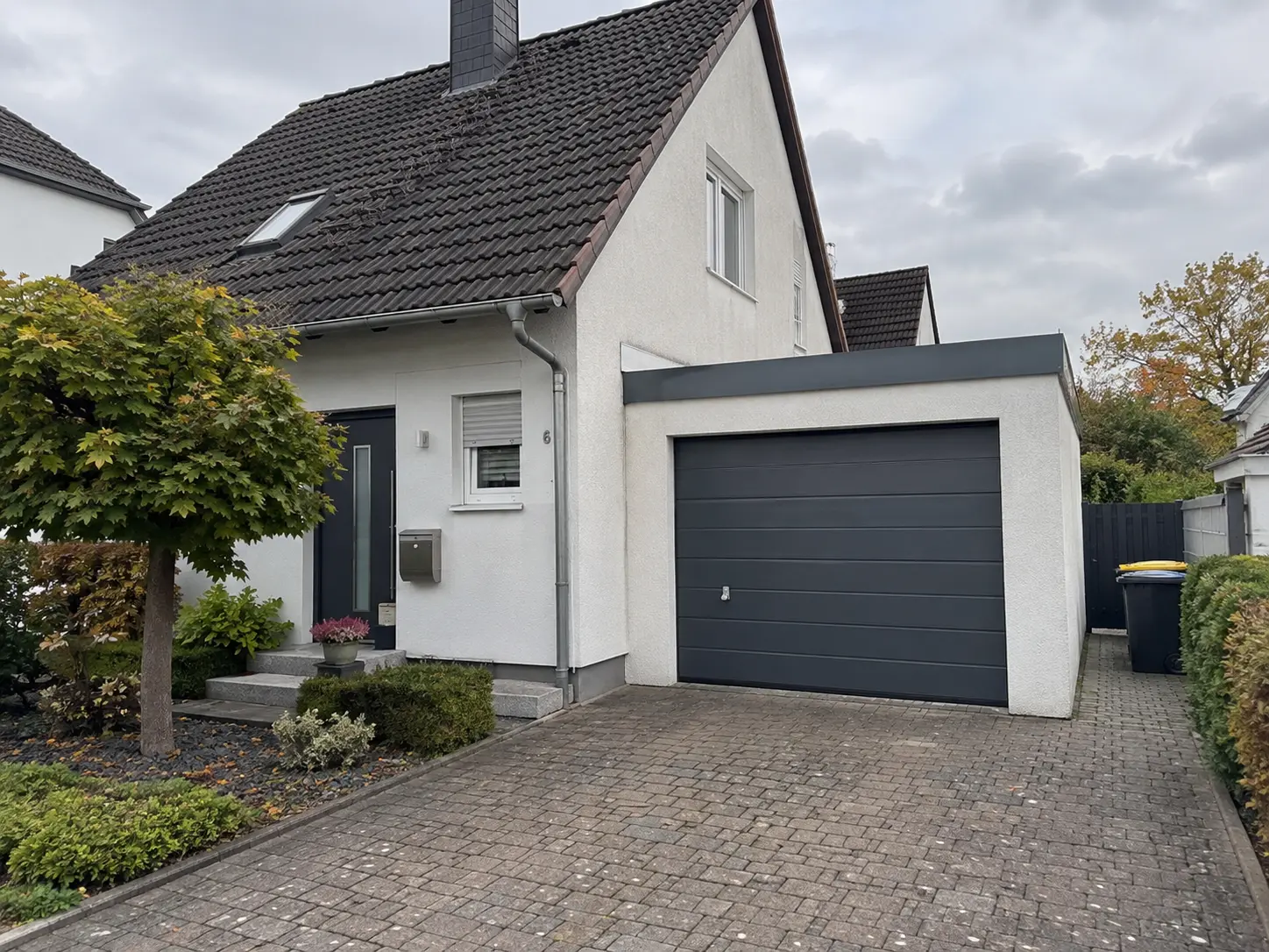 Einfamilienhaus mit Garage, gepflastertem Hof und bepflanztem Vorgarten
