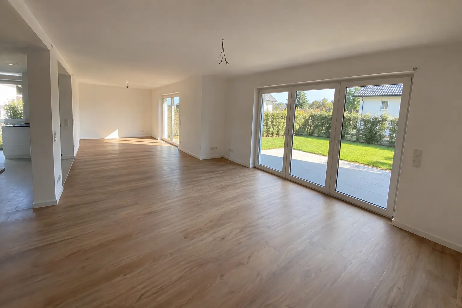 Offener Wohnbereich mit Holzboden und Terrassentüren zum Garten
